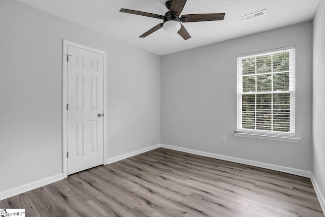 empty room with ceiling fan, a textured ceiling, and hardwood / wood-style flooring