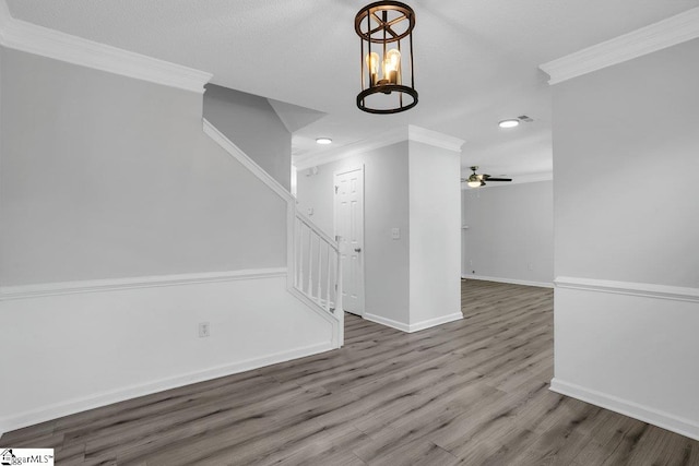 spare room featuring ceiling fan with notable chandelier, crown molding, and wood-type flooring