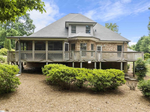 back of property featuring a sunroom, a shingled roof, and brick siding