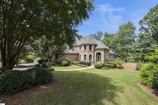 french country style house featuring a front lawn and brick siding