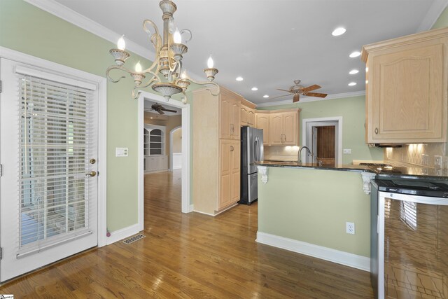 kitchen featuring tasteful backsplash, stainless steel fridge, light brown cabinetry, and hanging light fixtures