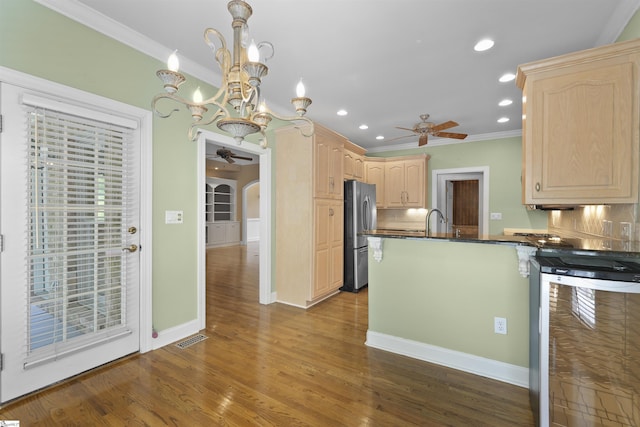 kitchen with arched walkways, dark countertops, visible vents, freestanding refrigerator, and light brown cabinets