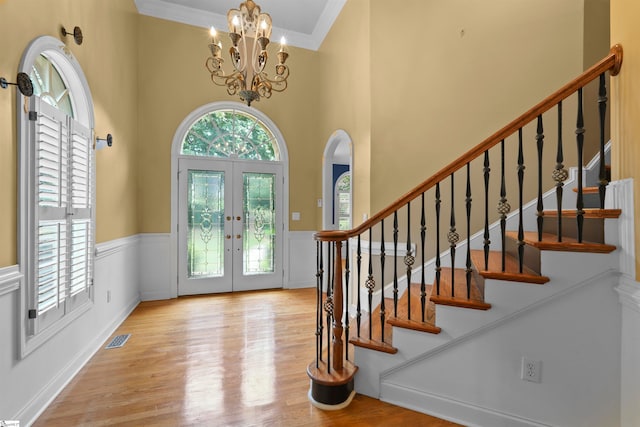 entryway featuring a chandelier, a healthy amount of sunlight, light hardwood / wood-style floors, and french doors