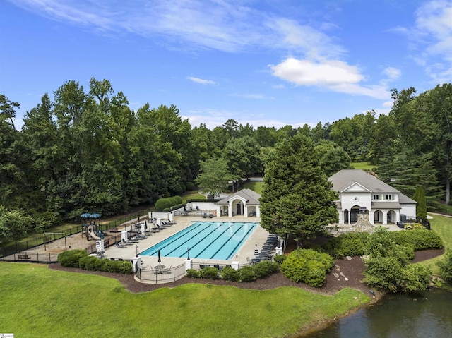 community pool featuring a patio, a lawn, and fence