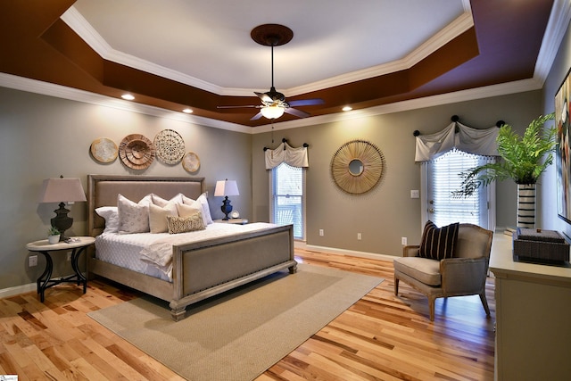 bedroom featuring ceiling fan, a raised ceiling, ornamental molding, and light hardwood / wood-style flooring