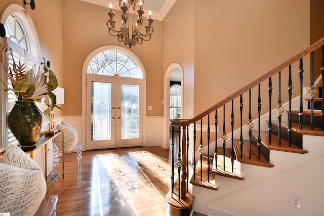 foyer featuring french doors, hardwood / wood-style flooring, an inviting chandelier, and ornamental molding