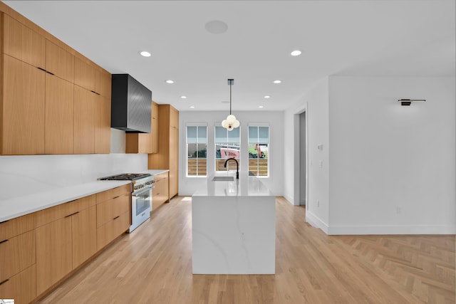 kitchen with light stone counters, an island with sink, pendant lighting, wall chimney range hood, and high end stove