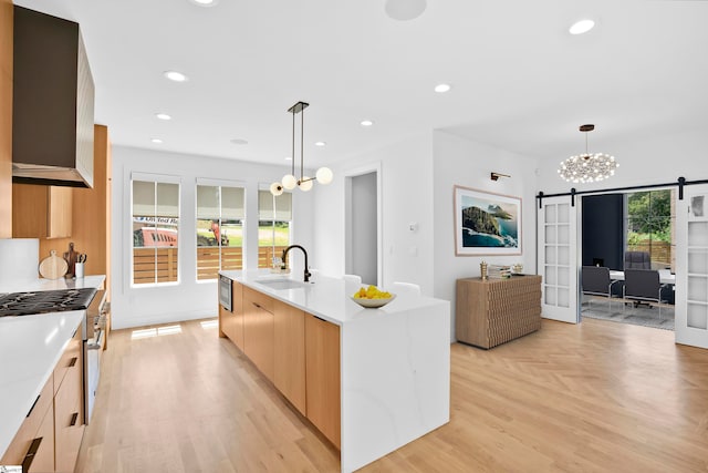 kitchen featuring sink, plenty of natural light, a kitchen island with sink, and hanging light fixtures