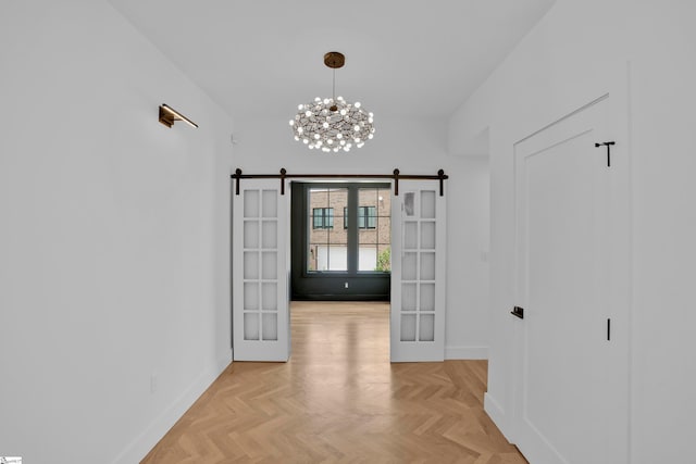 interior space featuring light parquet flooring, an inviting chandelier, french doors, and a barn door