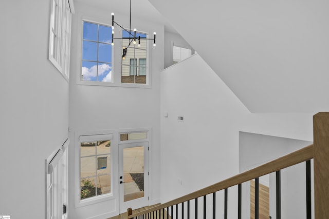 interior space with hardwood / wood-style flooring, a towering ceiling, and a chandelier