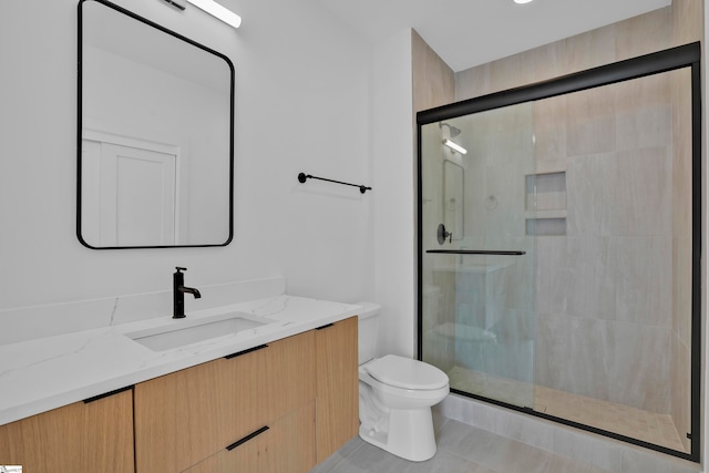 bathroom featuring tile patterned floors, a shower with door, vanity, and toilet