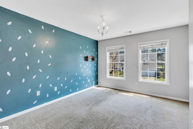 spare room featuring carpet floors, a notable chandelier, and a healthy amount of sunlight