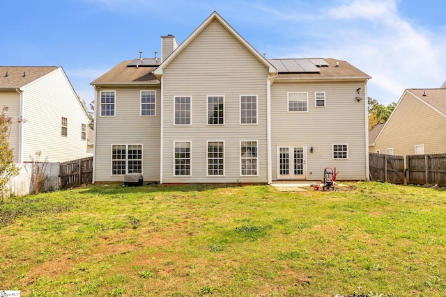 back of house featuring solar panels and a yard