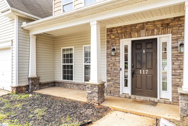 view of exterior entry with a porch and a garage