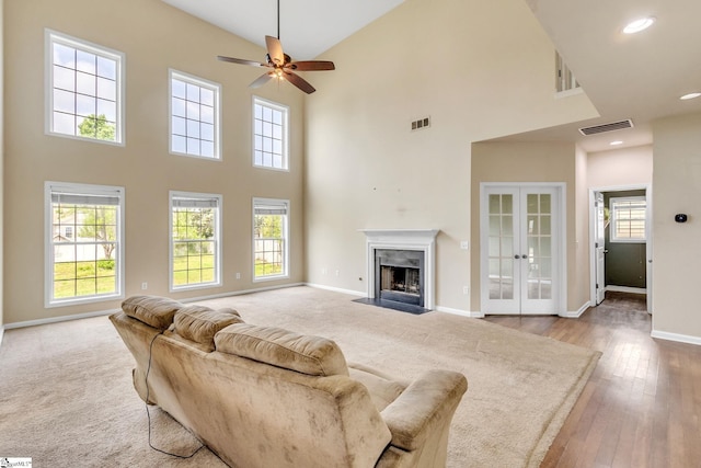 living room with a fireplace, light carpet, high vaulted ceiling, and ceiling fan