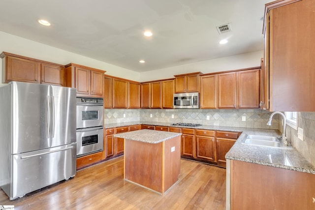 kitchen featuring backsplash, a kitchen island, light hardwood / wood-style floors, sink, and stainless steel appliances