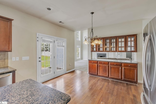 kitchen with backsplash, appliances with stainless steel finishes, pendant lighting, and hardwood / wood-style floors