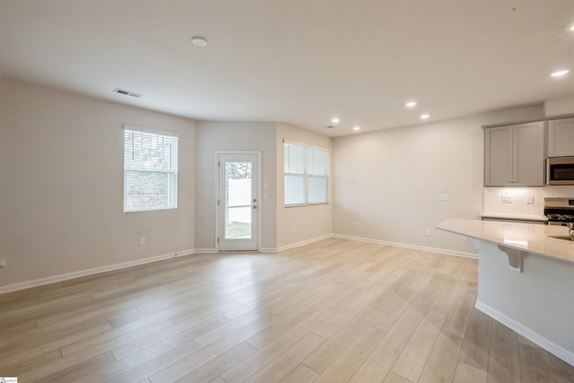 kitchen with a breakfast bar area, backsplash, light hardwood / wood-style floors, and stove