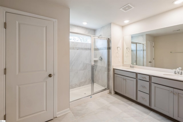 bathroom featuring an enclosed shower, double vanity, and tile patterned floors