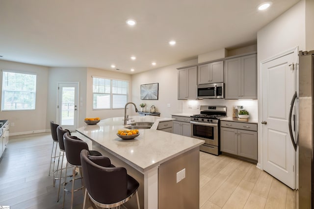 kitchen with sink, a kitchen breakfast bar, light hardwood / wood-style flooring, and appliances with stainless steel finishes