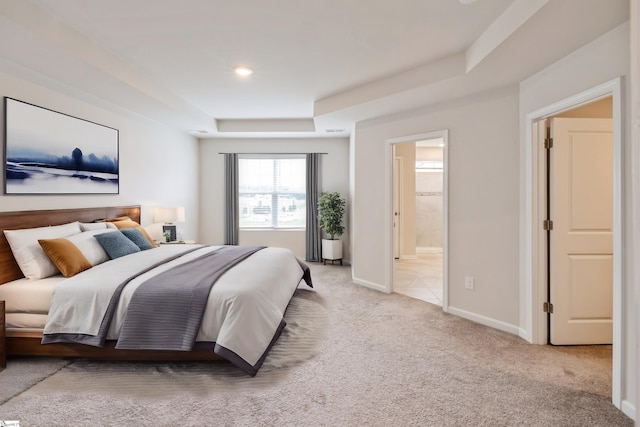 carpeted bedroom with a raised ceiling and ensuite bathroom