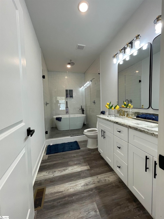 bathroom with a shower with door, toilet, vanity, hardwood / wood-style floors, and tile walls