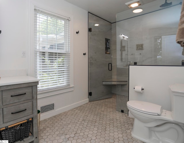 bathroom with tile patterned flooring, vanity, walk in shower, and toilet