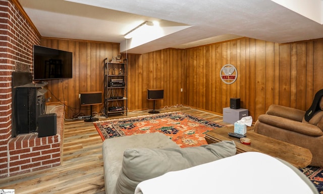 living room with brick wall, a wood stove, a textured ceiling, wooden walls, and wood-type flooring