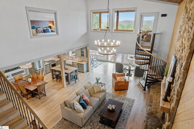 living room featuring lofted ceiling, wood-type flooring, and a notable chandelier