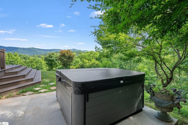 exterior space with a hot tub, a mountain view, and concrete flooring