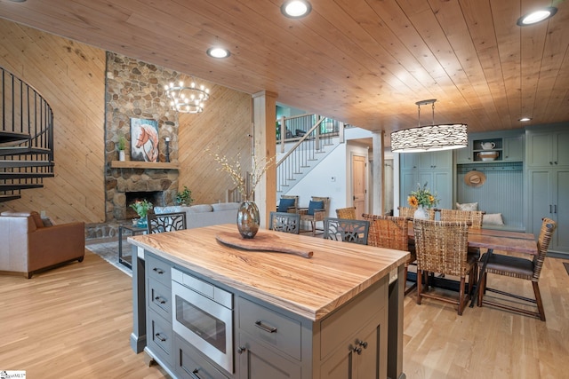 kitchen featuring pendant lighting, wood walls, a kitchen island, a fireplace, and stainless steel microwave