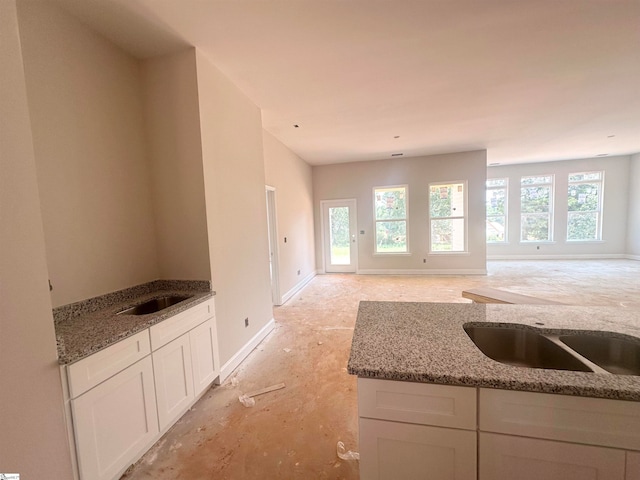 kitchen featuring white cabinets, a healthy amount of sunlight, and dark stone countertops