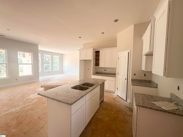 kitchen featuring white cabinets, light stone countertops, sink, and a center island with sink