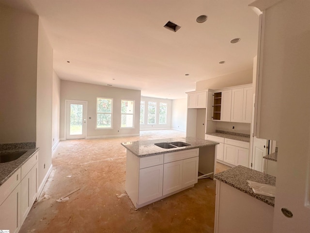 kitchen with white cabinets, light stone counters, and a kitchen island