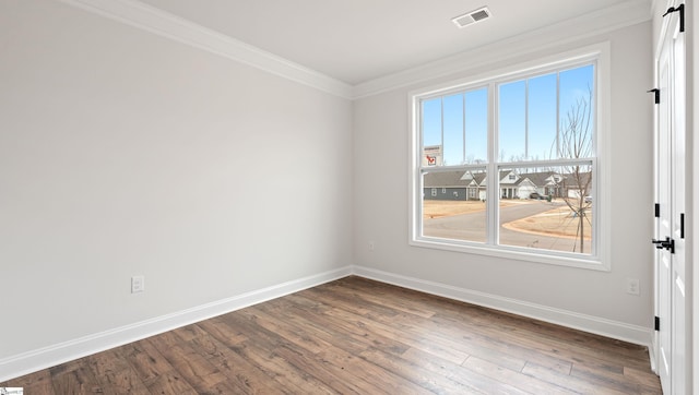 empty room with baseboards, visible vents, wood finished floors, and ornamental molding