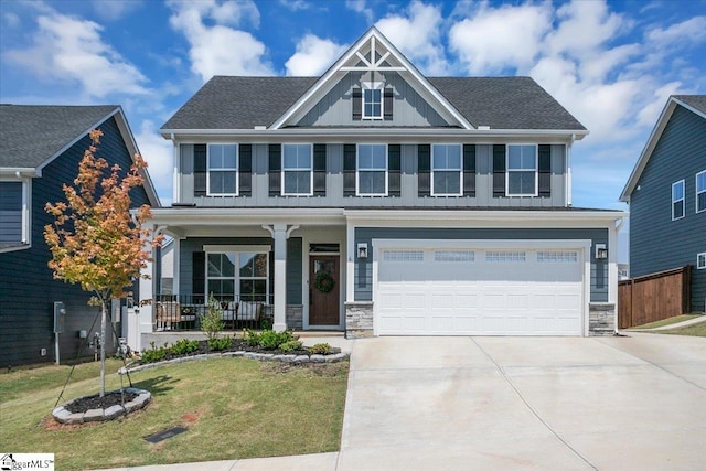 view of front of property featuring a front lawn, a garage, and covered porch