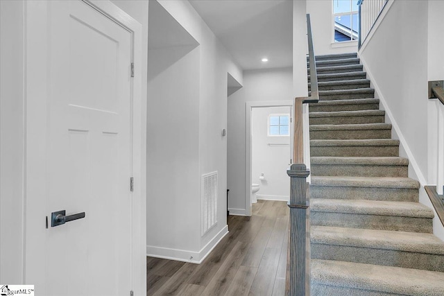 stairway with a healthy amount of sunlight and hardwood / wood-style flooring