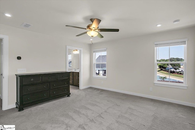 carpeted bedroom featuring ceiling fan, connected bathroom, and multiple windows