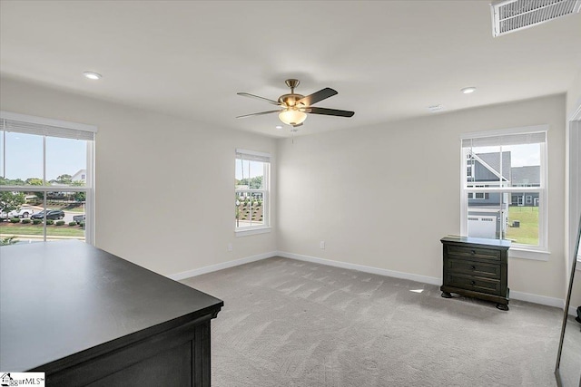 interior space featuring ceiling fan, light carpet, and a healthy amount of sunlight