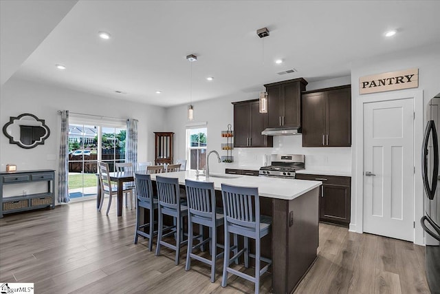 kitchen with sink, light hardwood / wood-style flooring, a center island with sink, and stainless steel gas range