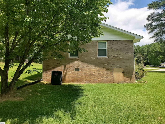 view of side of property with central AC and a yard