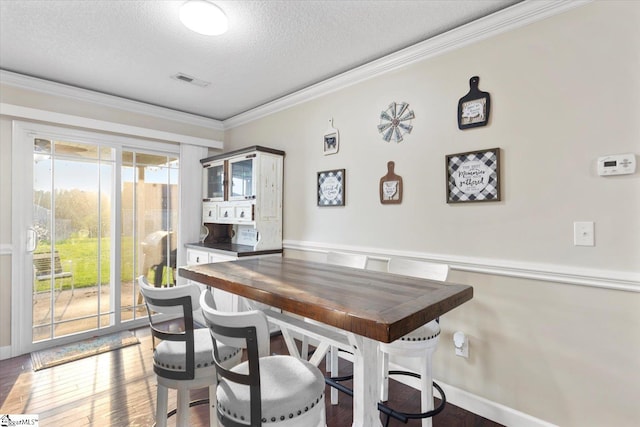 dining area featuring hardwood / wood-style flooring, ornamental molding, and a textured ceiling