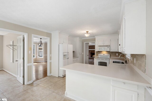 kitchen with light tile patterned floors, backsplash, kitchen peninsula, and white appliances