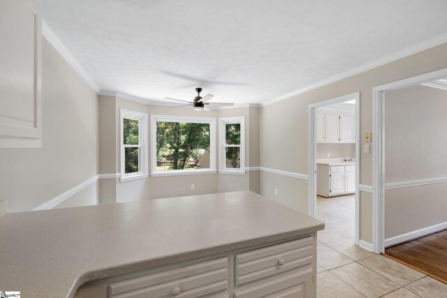 kitchen featuring ceiling fan, crown molding, a textured ceiling, and light wood-type flooring