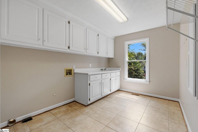 clothes washing area with light tile patterned floors, hookup for a washing machine, sink, and cabinets