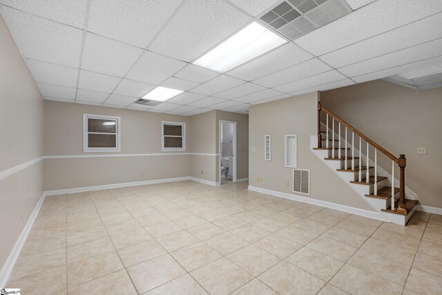 basement with light tile patterned floors and a drop ceiling