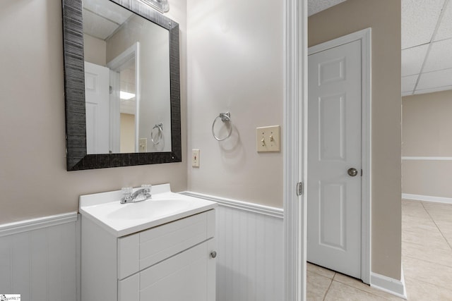 bathroom featuring tile patterned flooring, vanity, and a paneled ceiling