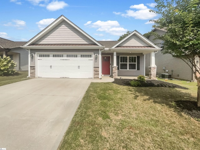 view of front of home featuring a garage, a standing seam roof, stone siding, and a front yard