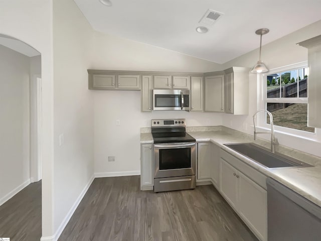 kitchen featuring lofted ceiling, stainless steel appliances, light countertops, pendant lighting, and a sink