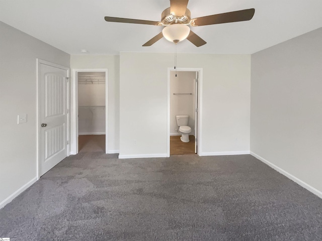 unfurnished bedroom with a closet, carpet, a walk in closet, and baseboards